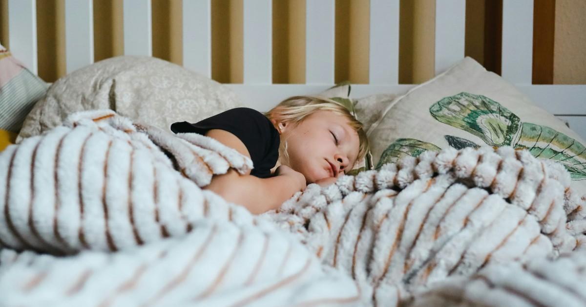 A blonde child is asleep in bed 