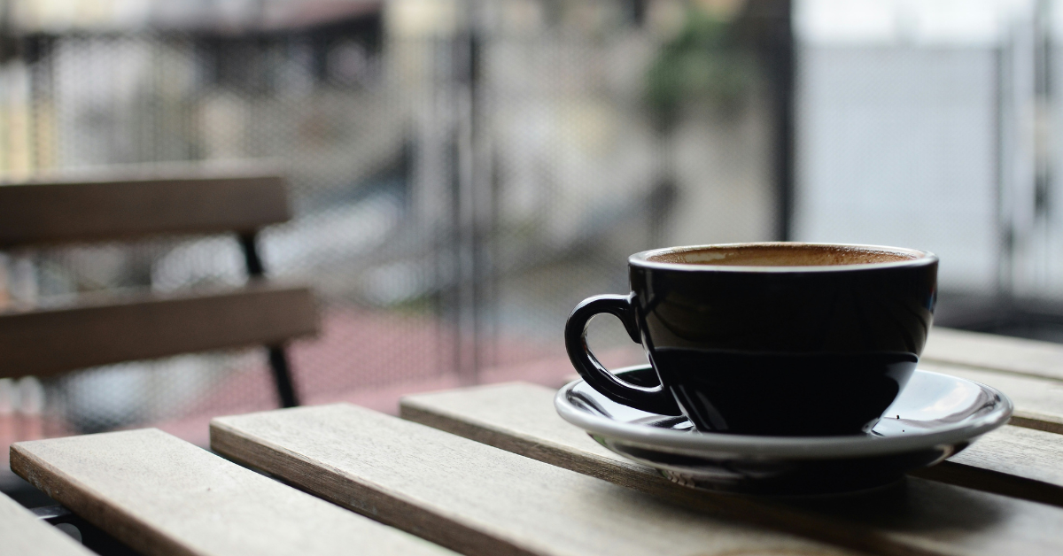 A steaming cup of coffee sits on a patio table