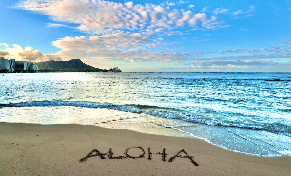 A beach in Hawaii with "aloha" in the sand.
