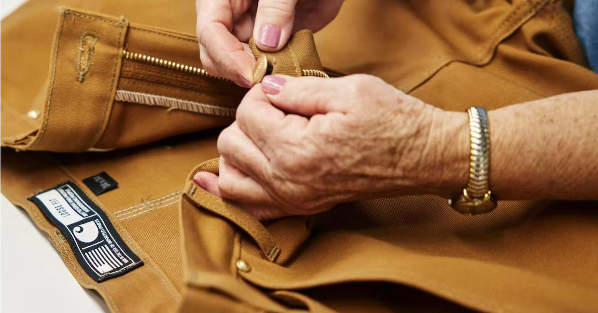 Person holds Carhartt khaki pants on table