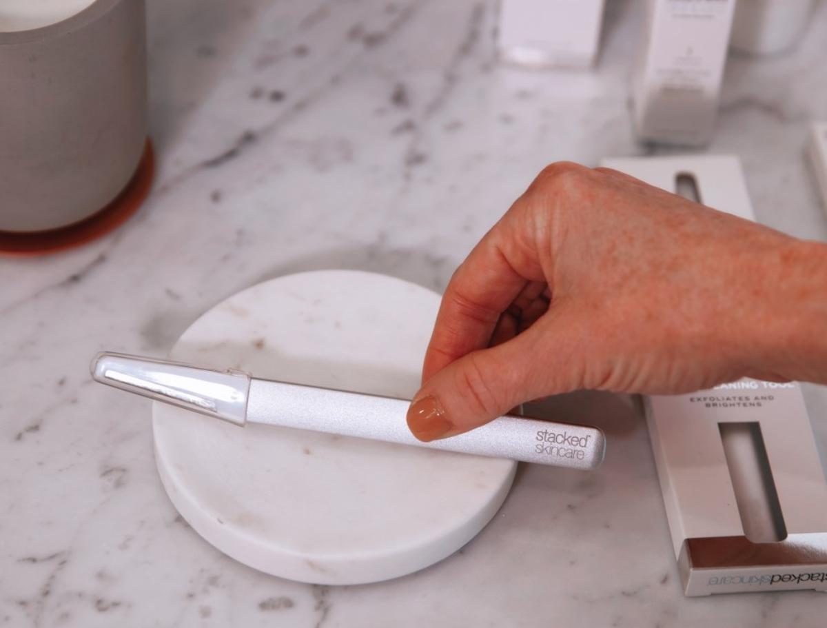 Person with dark spots holding StackedSkincare dermaplaner