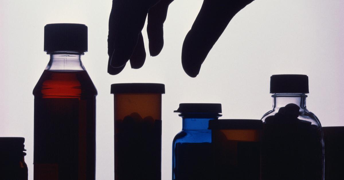 Hand reaches for medicine bottles in shadow