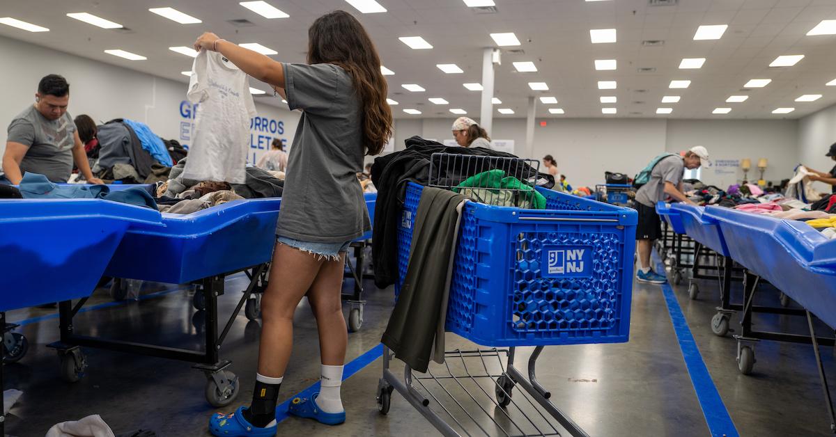 Woman holds up a shirt as she browses the blue bins in a thrift store