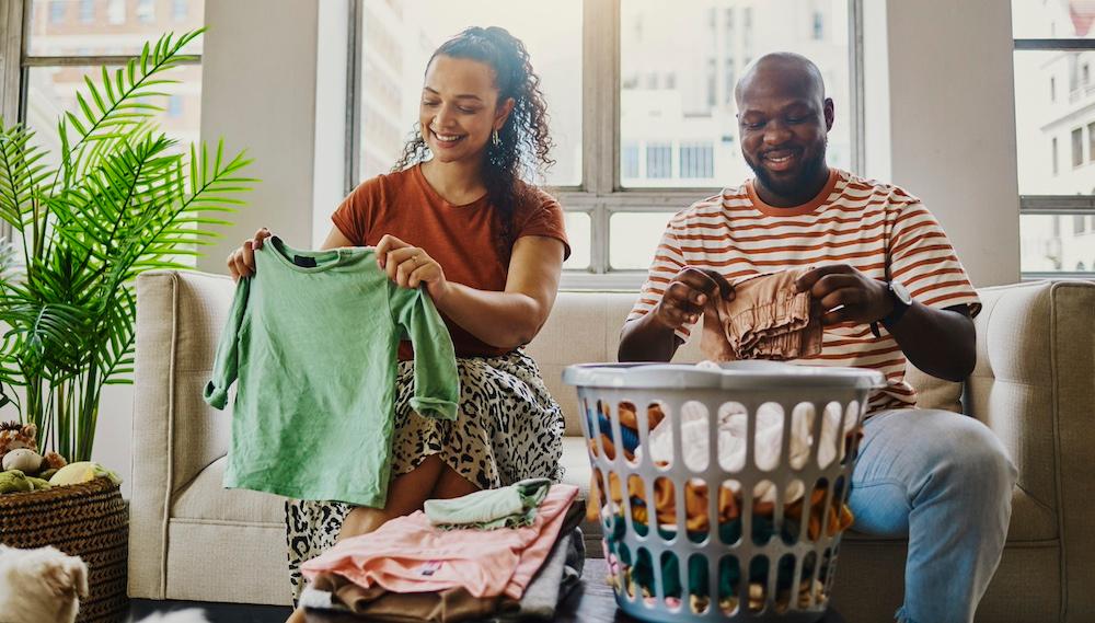 A couple folding laundry together in their living room.